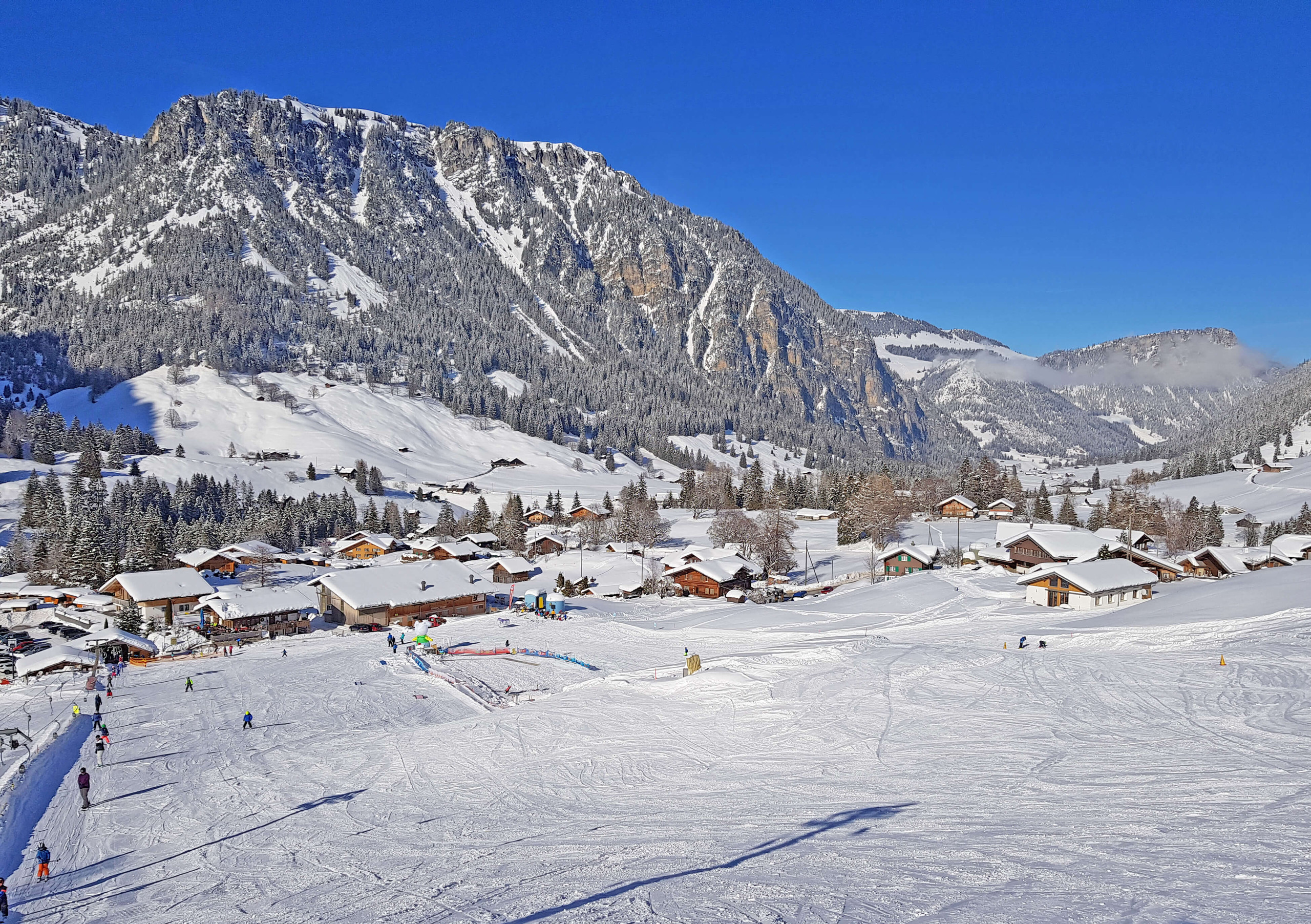 Winter sports enthusiasts enjoying the snowy landscape at Grimmialp ski resort in Switzerland, complete with a cozy chalet nestled amidst snow-clad trees.