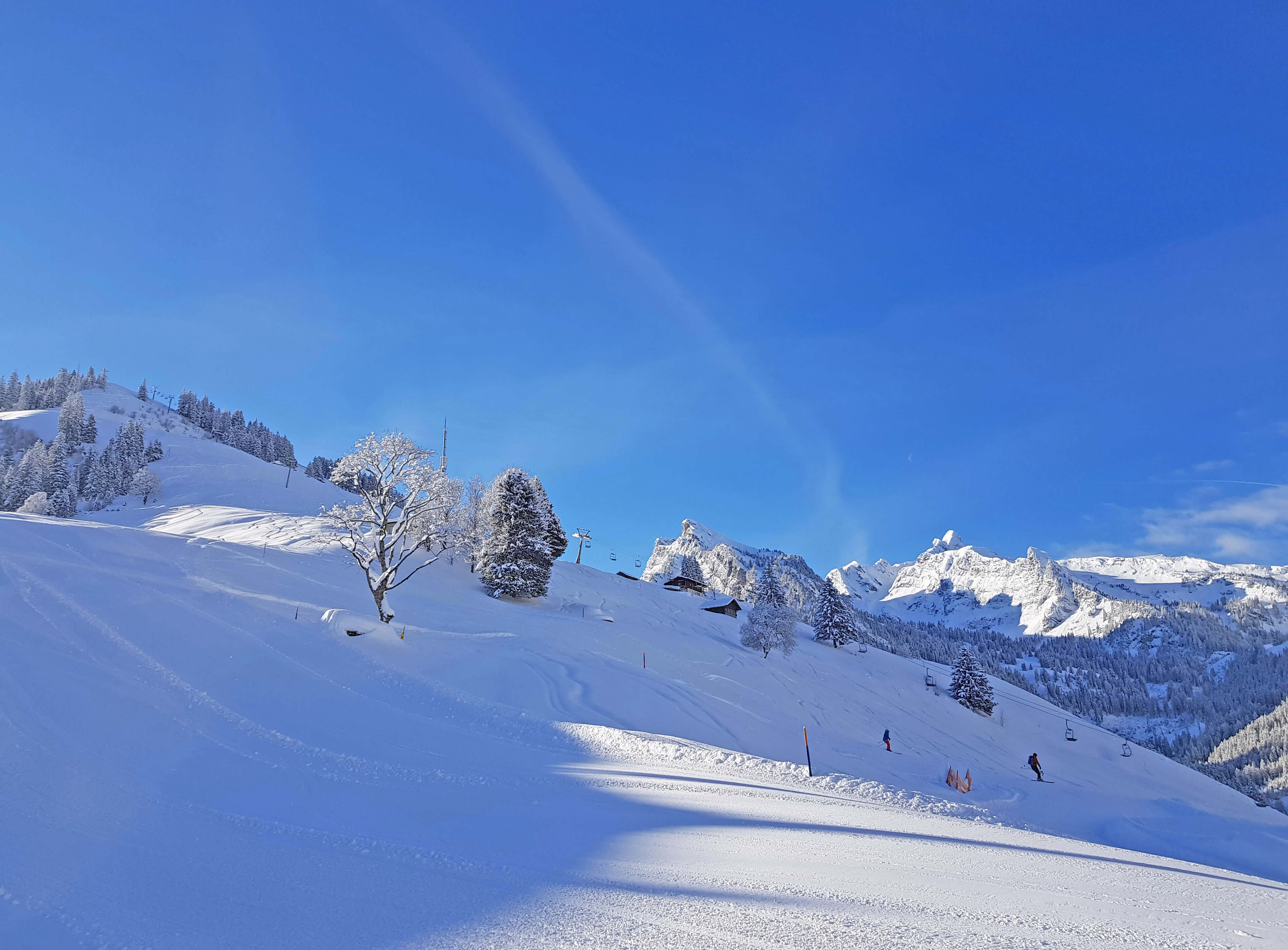 Winter sports enthusiasts enjoying the day at the ski resort in Grimmialp, Switzerland with a charming challet nearby, surrounded by a serene winter landscape and mountains.