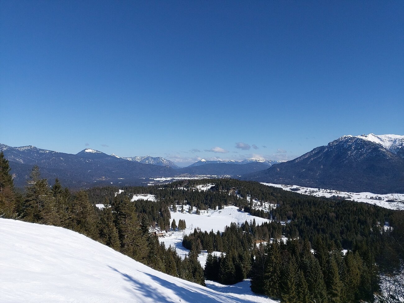 A vibrant winter sport scene at Kranzberg ski resort in Upper Bavaria Germany. Skiers enjoying the sunlit mountain peak with a charming chalet nestled amidst the snowy landscape.