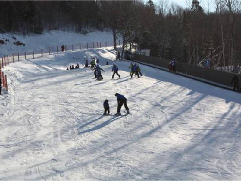 A vibrant winter sports scene at Mont-Saint-Mathieu in Quebec, Canada, showcasing a bustling ski resort with a chalet in the background.
