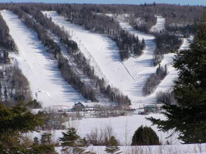 An invigorating view of Mont-Saint-Mathieu in Quebec, featuring a ski resort bustling with winter activity. Snow-covered slopes stretch out below a bustling ski lift, establishing this as a thriving winter sports centre.