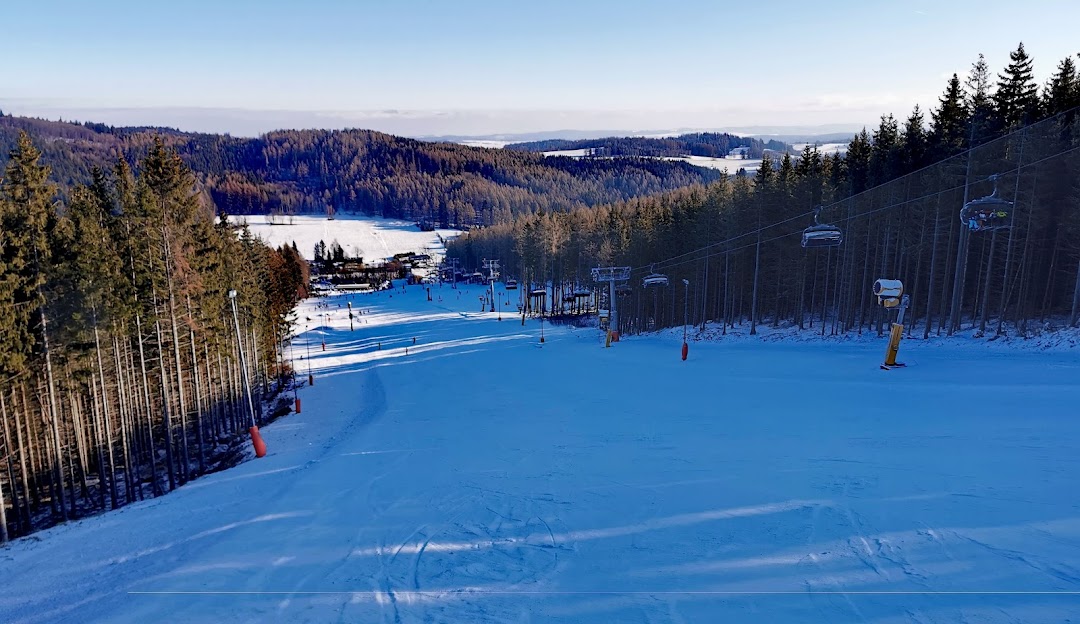 Ski resort scene in Kopřivná, Malá Morávka, Czech Republic with a ski lift amidst stunning winter scenery featuring snow-covered slopes for winter sports.