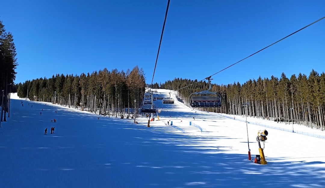 View of the Kopřivná ski resort in Malá Morávka Czech Republic displaying a vibrant winter sports scene with a ski lift and a skier in action.