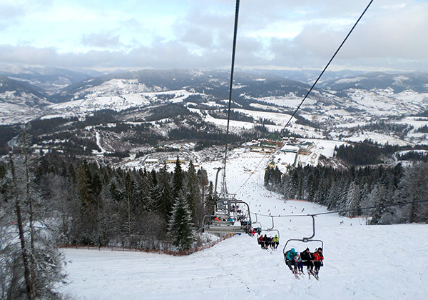 A bustling winter sports scene at Play in Plav'ya Lviv Ukraine. Visible are a functional ski lift a classic challet and snow-covered slopes at this lively ski resort.