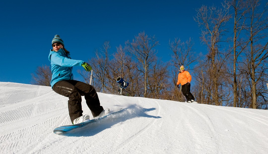 A snowboarder skillfully navigating the slopes at Roundtop in Lewisberry Pennsylvania surrounded by a winter landscape.