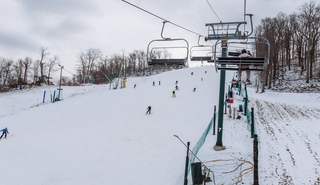 Winter sports scene at Roundtop in Lewisberry Pennsylvania with a ski lift transporting skiers up the snow-covered slopes of the ski resort.