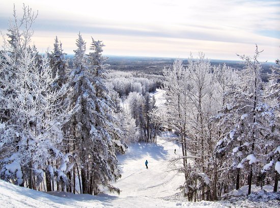 Winter scene at Mount Jamieson ski resort in Northern Ontario, Canada. Skiers enjoy the slopes under the ski lift amidst picturesque winter scenery.