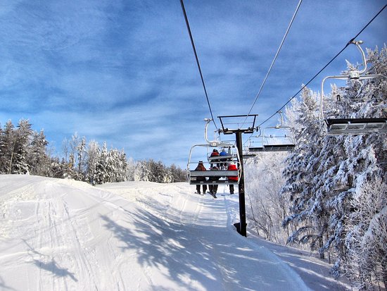 Winter scene at Mount Jamieson ski resort, Northern Ontario, with a ski lift in view and a skier undertaking winter sports amidst the beautiful winter scenery.