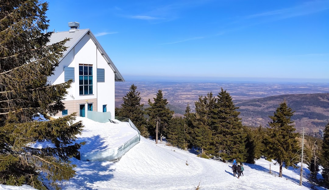 Winter sports scene at Świeradów Zdrój SKI & SUN, a popular ski resort in Świeradów-Zdrój, Poland, featuring a stunning snowy landscape, mountains in the backdrop and a cozy mountain hut.