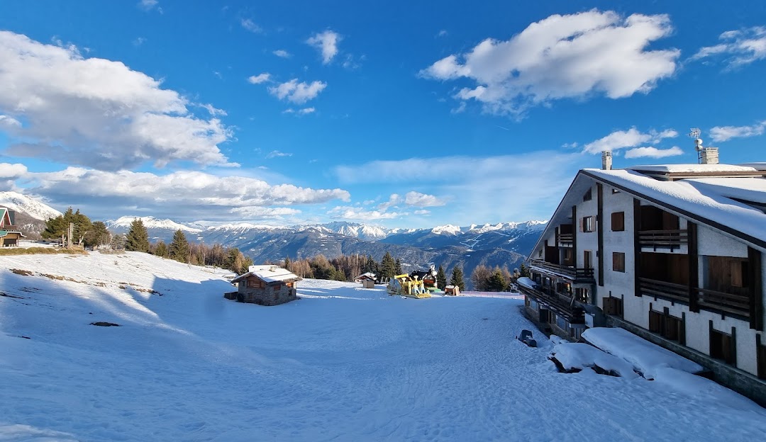 View of Alpe Teglio ski resort in Prato Valentino, Italy showcasing stunning winter scenery, sporting activities, and a cozy chalet amidst a tranquil snow-covered landscape.