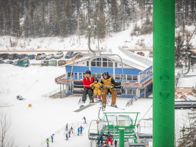 Skiers enjoying a day on the slopes at Hidden Valley, a ski resort in Elkwater, Alberta, Canada. A ski lift transports people up the hill, completing the winter sports scene.