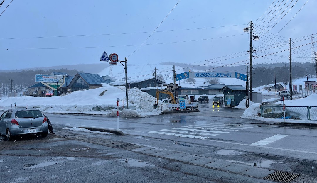 A vibrant winter sports scene at Hirugano Kogen in Japan, featuring a bustling ski resort with a snow-covered chalet amidst an enchanting winter landscape.