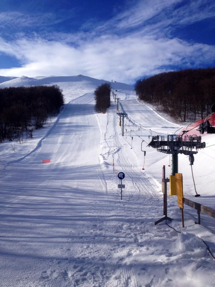 View of Sassotetto's snow-covered ski resort in Macerata, Italy, showcasing a ski lift, chalet, and stunning winter scenery, embodying the charm of winter sports.