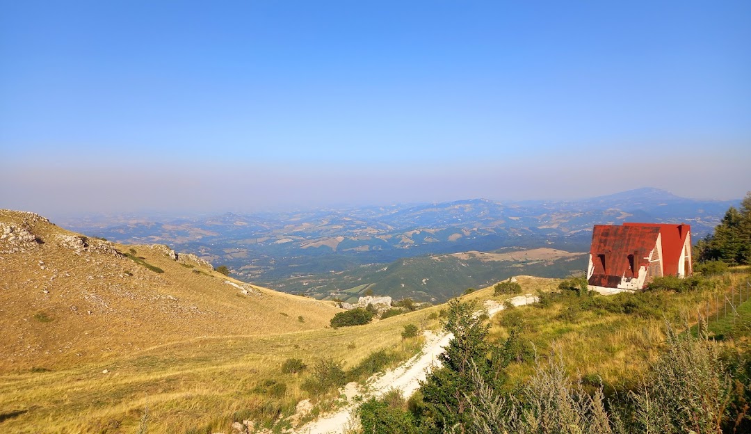 A charming chalet rests within the scenic backdrop of Sassotetto's mountains in Macerata Italy. A mountain bike nearby suggests an adventurous day all beneath a welcoming sunny sky.