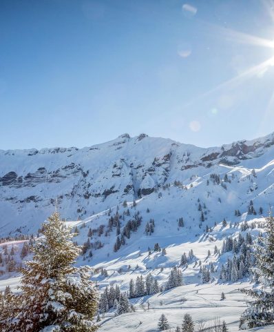 A scenic winter image from Megève, France showcasing a bustling ski resort amidst pristine snowy landscape, with a traditional challet nestled in the background.
