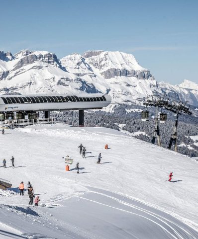 Scenic view of Megève in France, showcasing a bustling ski resort with lively winter sports scene. A charming chalet and ski lift are also faintly visible.
