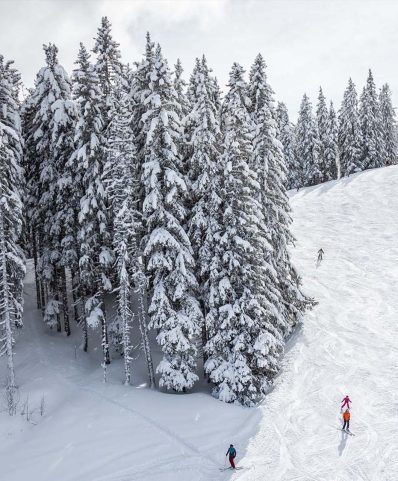 Winter sports scene at the ski resort of Megève in France, featuring a skier on the snowy slopes, with a ski lift in the distance and a group of skiers enjoying the day.