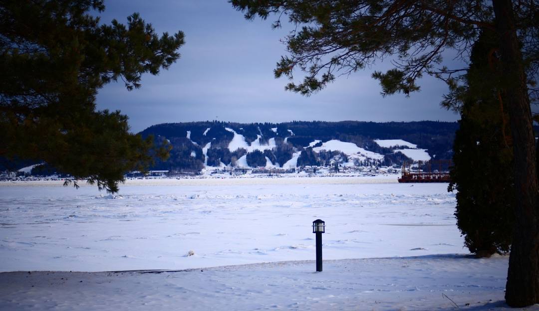 Winter sports scene in Mont-Bélu, Saguenay-Lac-Saint-Jean, featuring a charming chalet amidst stunning winter scenery, with a serene lake in the backdrop.