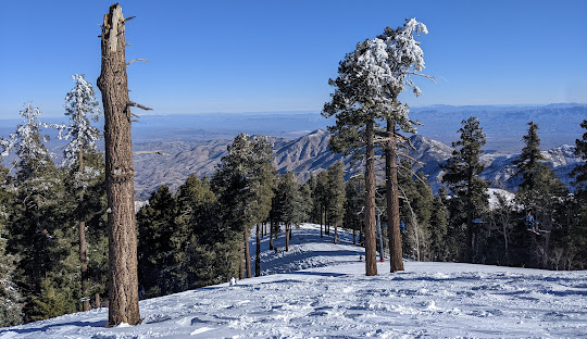 Winter sports enthusiasts enjoying a day at Mt Lemmon Ski Valley in Arizona. The mountainous winter scenery serves as the backdrop to a bustling ski resort.