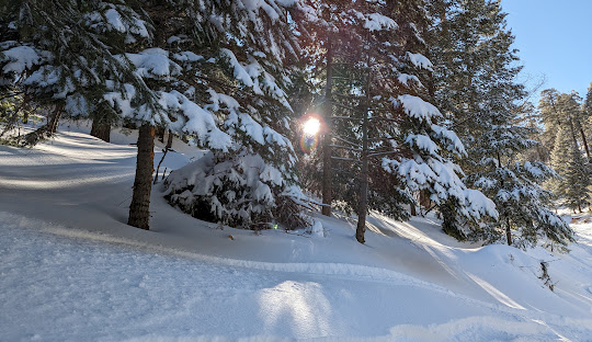 Winter sports scene at Mt Lemmon Ski Valley, Arizona, featuring a snowmobile against a breathtaking snowy landscape on a sunny day.