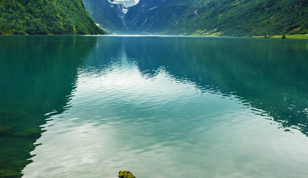 An image capturing the serene winter beauty of Norway Mountain in Michigan, USA. A stunning lake is visible in the foreground with a distant mountain vaguely seen beyond under a wintry sky.