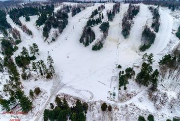 Winter view at Norway Mountain, Michigan, showcasing a bustling winter sports center surrounded by stunning snow-frosted scenery, with sports enthusiasts enjoying skiing at the resort.