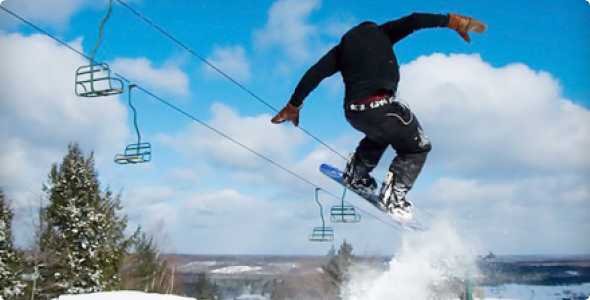 A snowboarder skillfully gliding down the snowy slopes of Norway Mountain in Michigan, USA, clad in vibrant gear against the white landscape.
