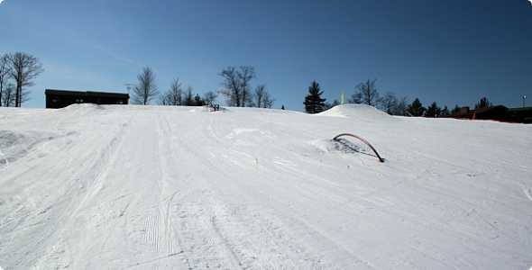 A winter sports scene at Norway Mountain in Michigan featuring a skier in action. The lively ski resort with a charming chalet contributes to the atmosphere of an active winter sports center.