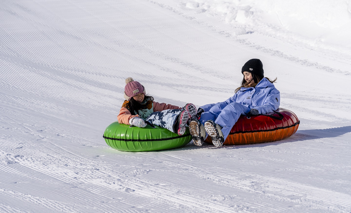 Rusutsu in Japan - two people sled down a hill in the snow.