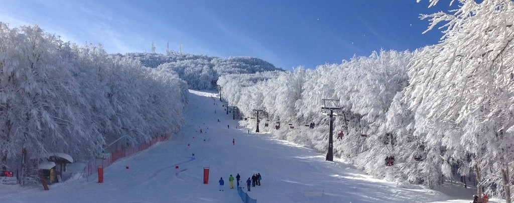 Winter sports enthusiasts at the Monte Amiata ski resort in Siena, Italy. The scenic landscape is dotted with ski lifts and cozy chalets amongst snow-covered mountains.