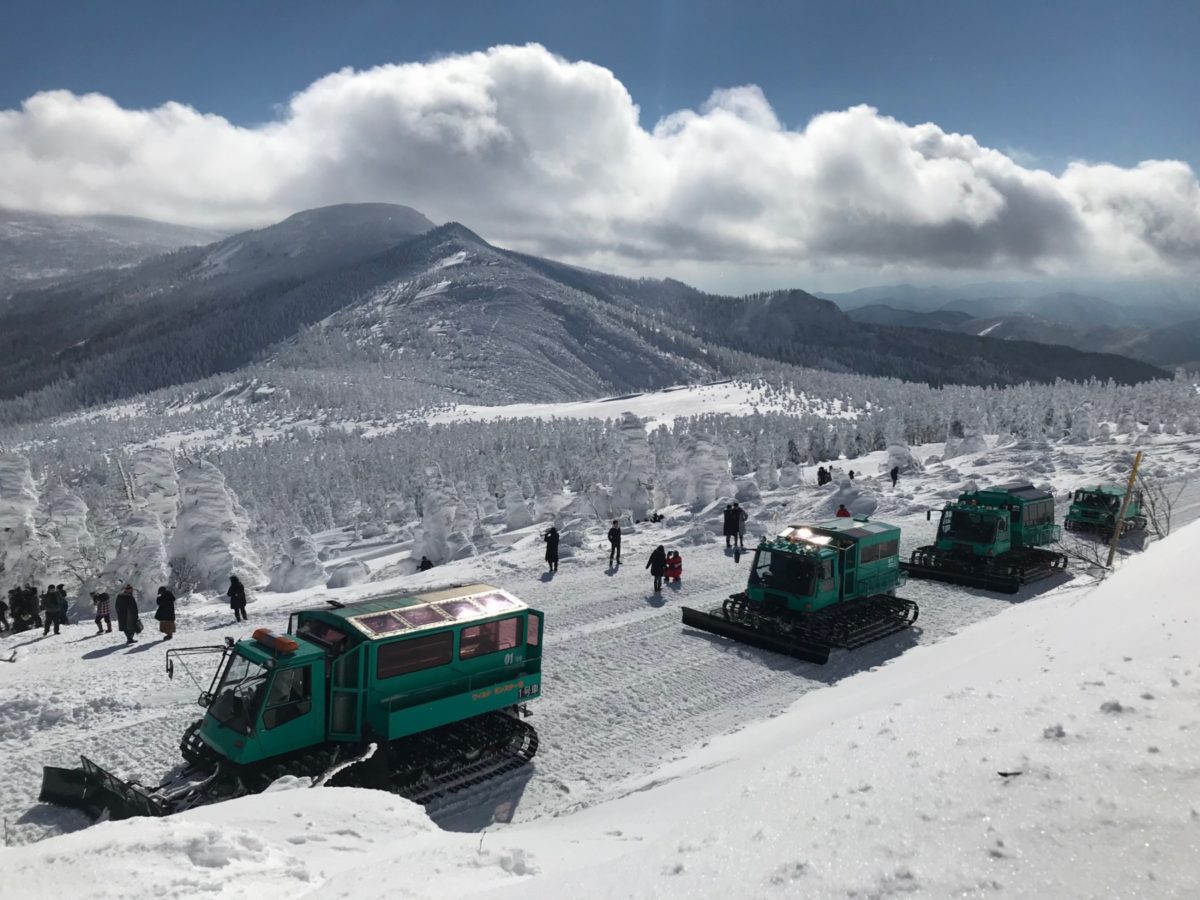 Zao Sumikawa in Japan - a group of people standing on top of a snow covered mountain.