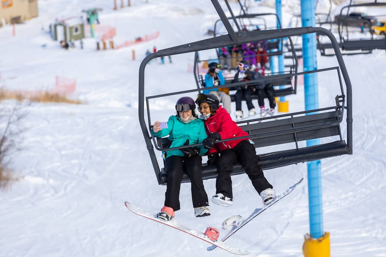 Misery Mountain in Canada - two people on a ski lift in the snow.