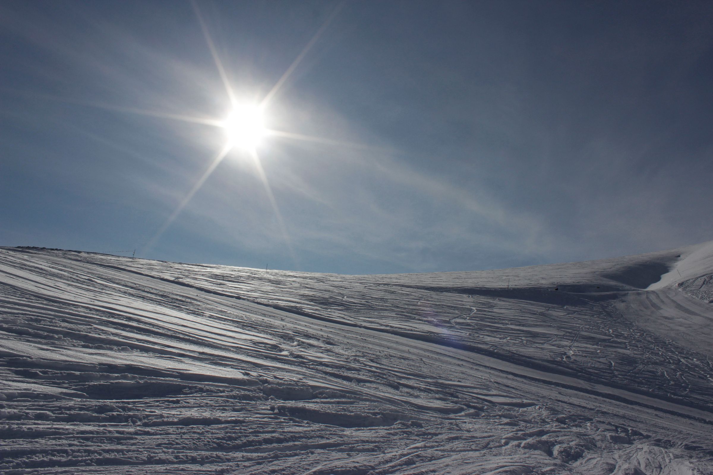 A winter sports enthusiast enjoying a sunny day skiing down the slopes of the picturesque Seli ski resort in Kato Vermio Greece with a charming chalet in view.