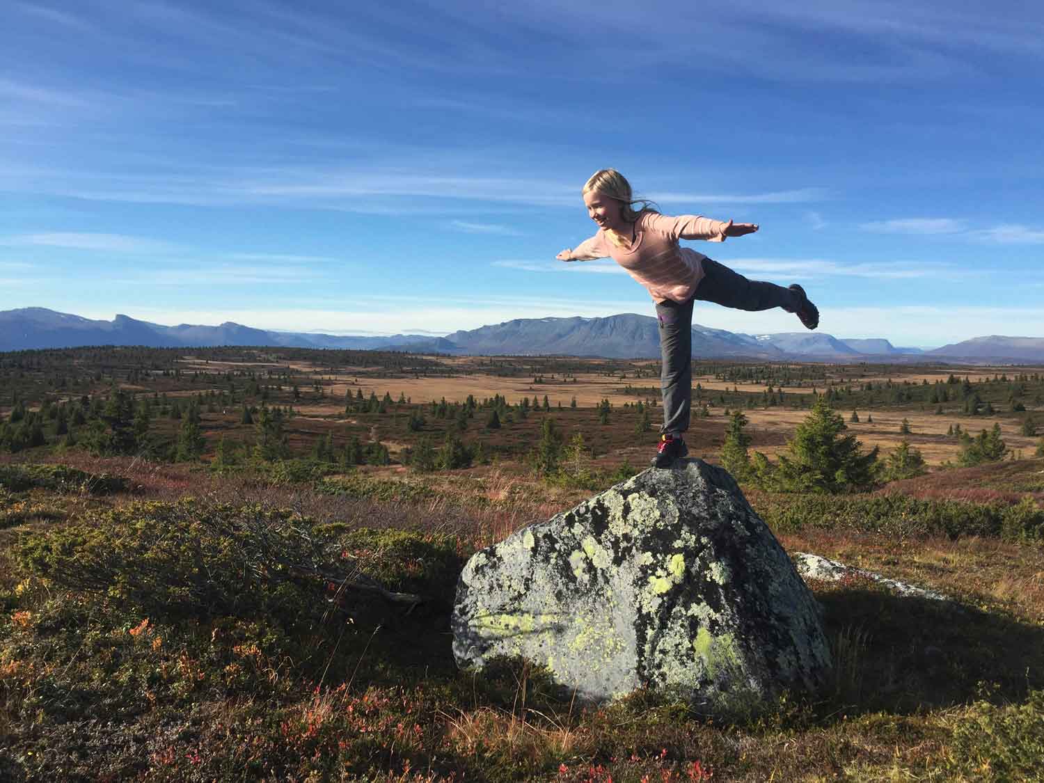 A skier and snowboarder enjoy a sunny day on the slopes of Golsfjellet mountain in Gol, Norway. A picturesque chalet rests nearby amidst the snow-covered landscape.