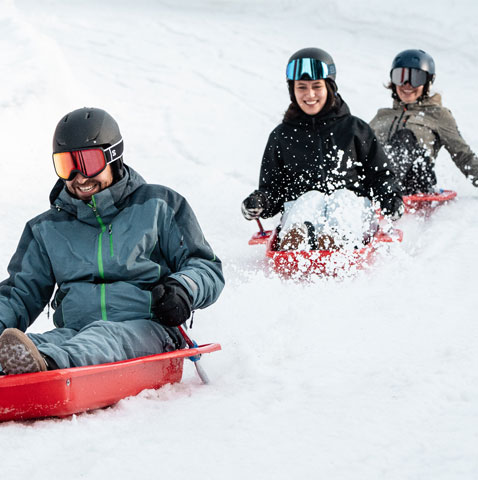 Winter sports scene at Les Arcs, Peisey-Vallandry in France showcasing a skier and a group of people skiing, possibly a family and a snowmobile nearby.