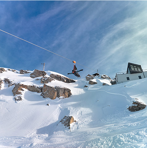 Skier gliding down a slope at Les Arcs | Peisey-Vallandry ski resort in Auvergne-Rhône-Alpes, France, with a mountain hut and ski lift nearby, basking in a wintry ambiance.