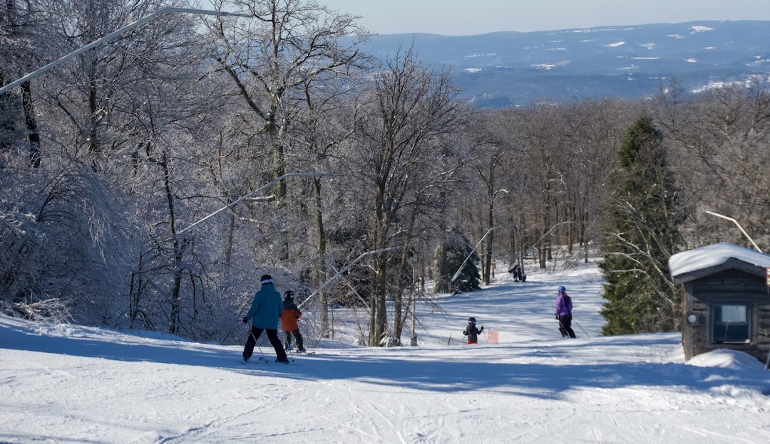 A family enjoying a winter sports scene on the beautiful snowy slopes of Laurel Mountain Ski Resort in Boswell Pennsylvania accompanied by other skiing enthusiasts.