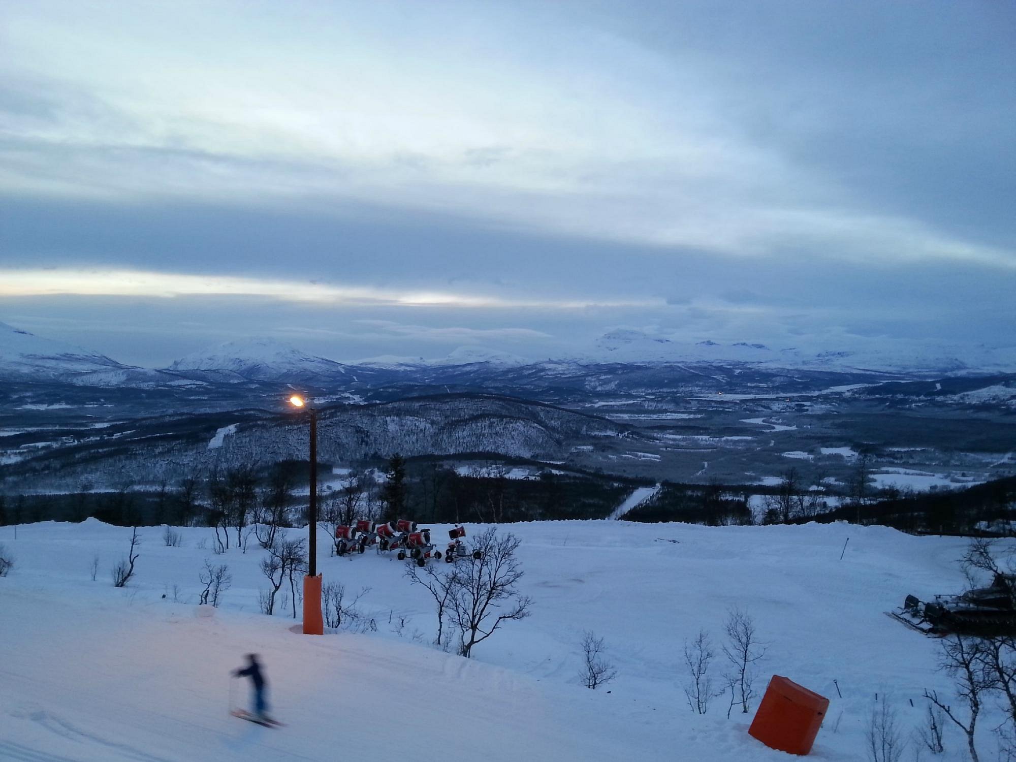 Målselv Fjellandsby, Moen, Troms, Norway featuring a bustling winter sports scene with a charming chalet nestled amid stunning winter scenery. In the backdrop, a ski resort thrives, portrayed in a beautifully serene winter environment.