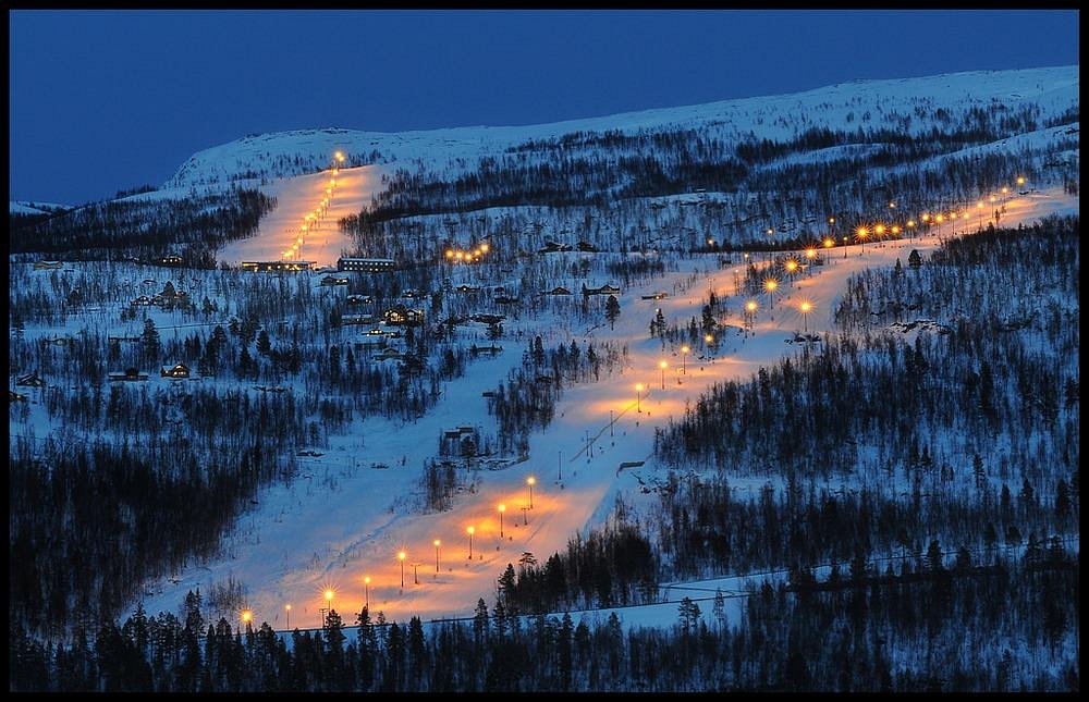 Scenic view of Målselv Fjellandsby ski resort in Moen, Troms, Norway. The image captures stunning winter scenery with skiers enjoying the slopes and a ski lift in the background.