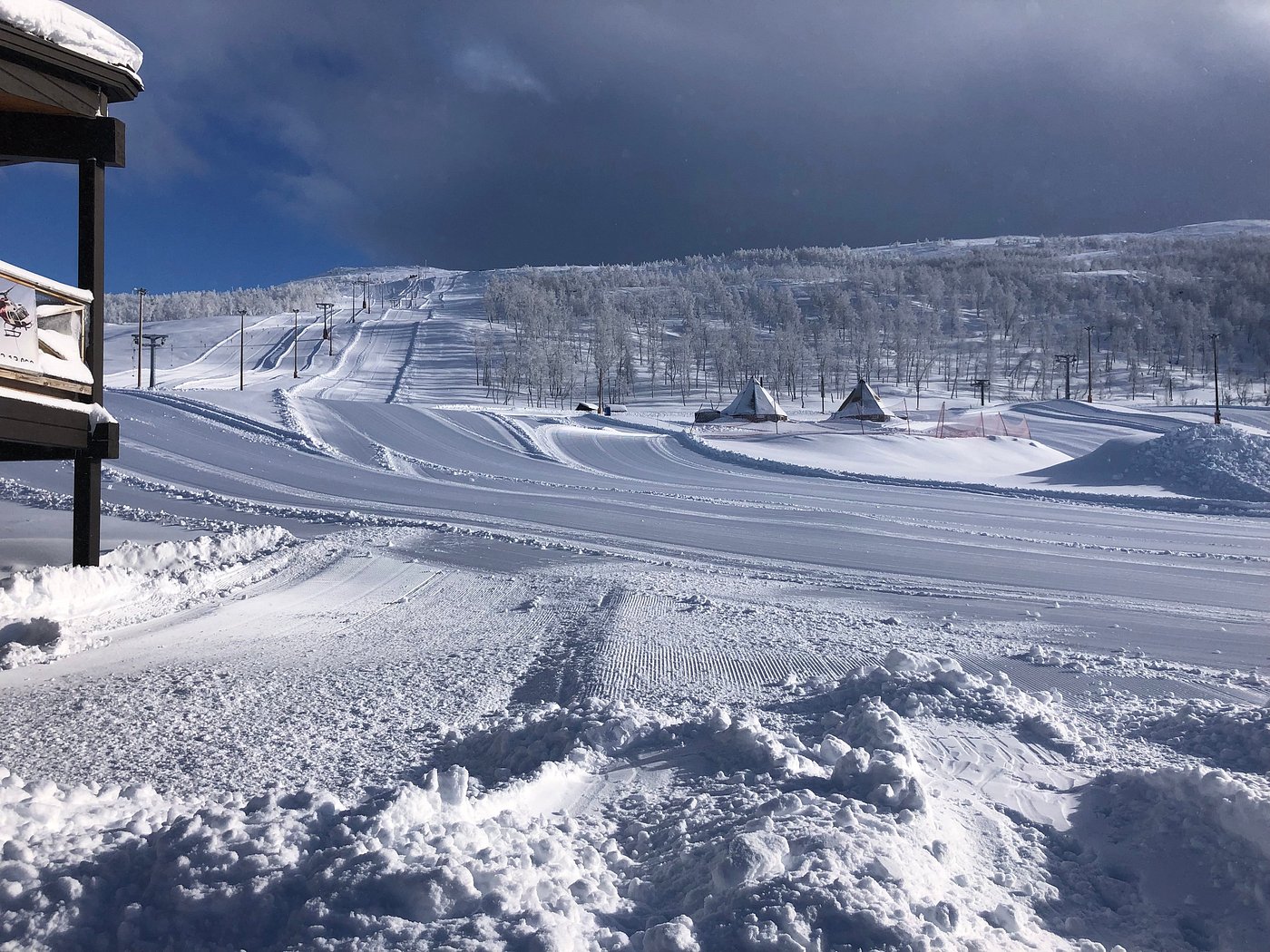 A winter scene at Målselv Fjellandsby ski resort in Moen, Troms, Norway. A chalet is nestled among snow-covered slopes bustling with winter sports activities.