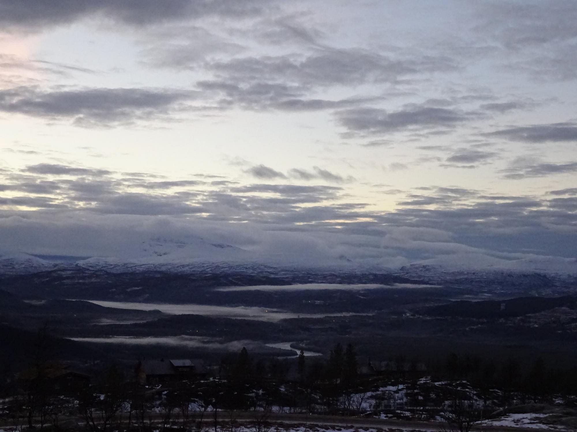 Winter scenic view of Målselv Fjellandsby in Moen, Troms, Norway, featuring a snowy mountain landscape, an active winter sports scene, and a charming chalet nestled among the snow.