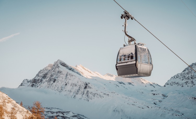 A winter sports scene at Scanno-Monte Rotondo in Abruzzo, Italy, featuring a ski lift and a chalet with a skier enjoying the ski resort.