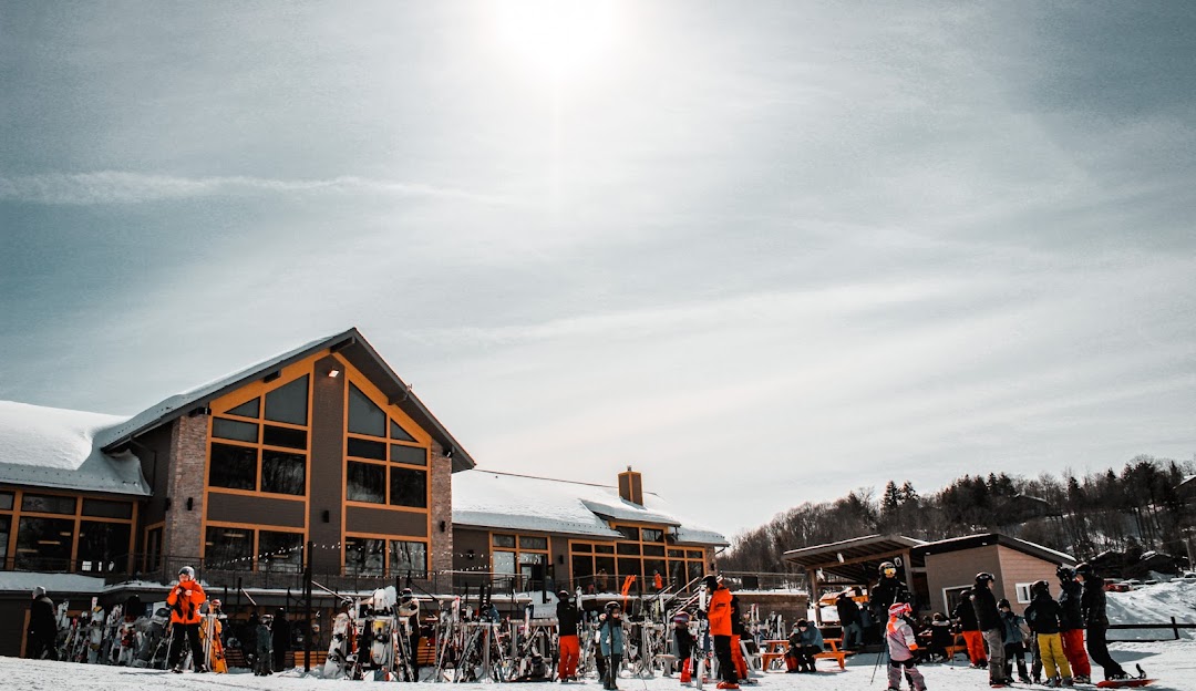 Winter at Vallée du Parc ski resort in Shawinigan Quebec featuring skiers and snowboarders with a ski lift in the background surrounded by stunning snow-laden trees.
