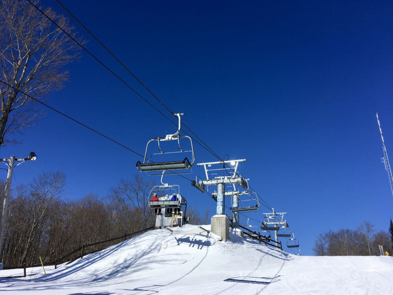 Winter scene at Vallée du Parc in Quebec Canada showing a ski lift in operation over snow-covered slopes. Skiers are enjoying the ski resort with wide mountainous vistas.