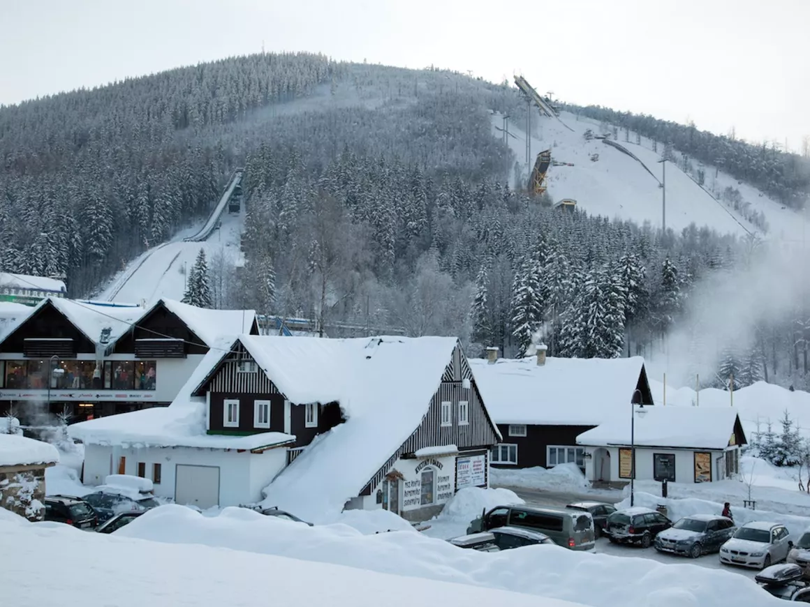 Čertova hora – Harrachov in Czech Republic - a snow covered ski slope with a ski lift in the background.