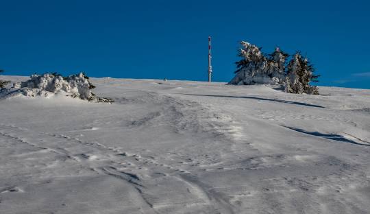 A picturesque chalet nestled in Martinské Hole, Slovakia. The prominent ski resort features a ski lift against the backdrop of a snow-laden mountain, providing a classic winter sports scene.
