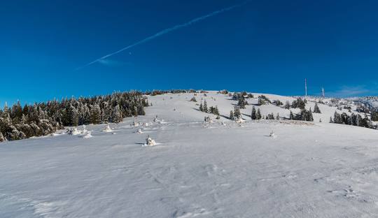 Scenic view of a winter sports scene at Martinské Hole ski resort, featuring a charming challet, active ski lift, and snow-covered slopes in Žilina, Slovakia.
