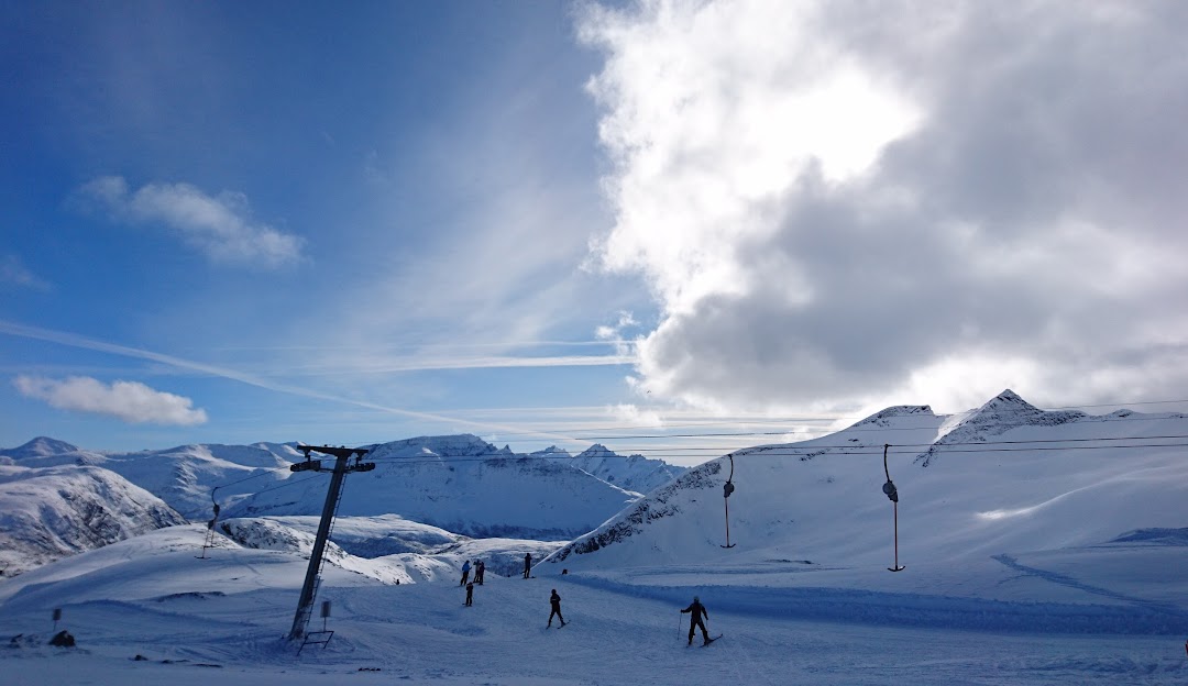 A winter scene at Sunnmørsalpane Skiarena Fjellsætra in Straumgjerde, Norway, featuring a charming chalet and a ski resort. Skiers take to the snow-covered slopes, accessing them via a ski lift.