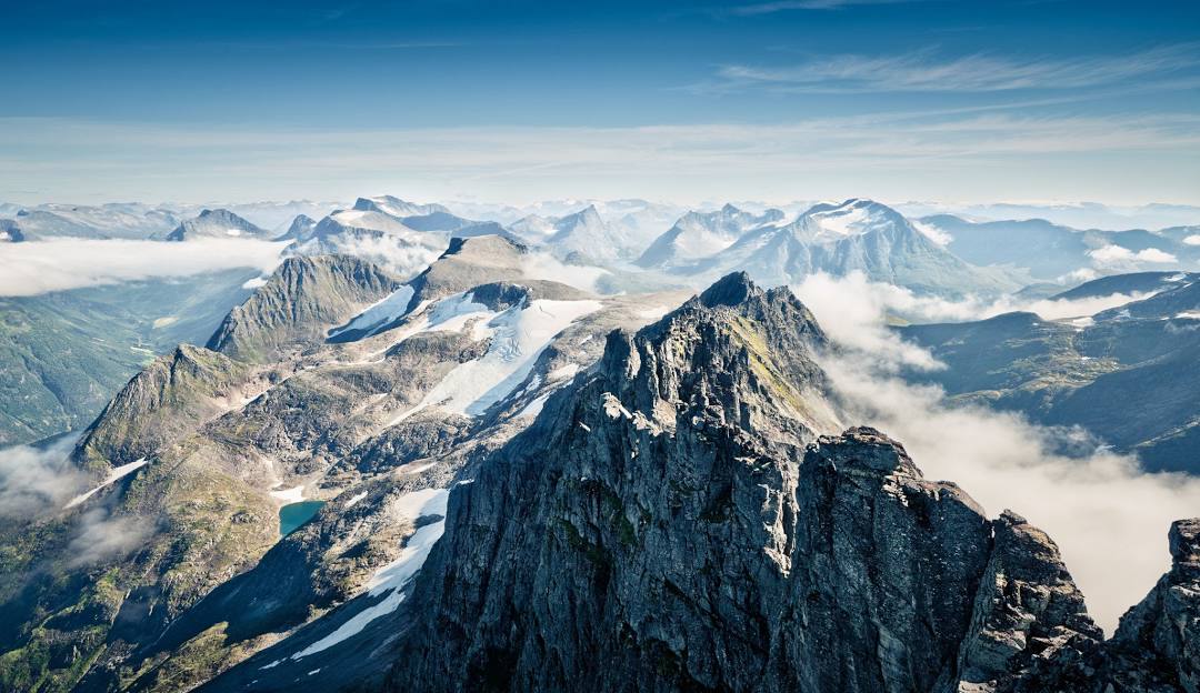 View of the scenic Sunnmørsalpane Skiarena Fjellsætra in Straumgjerde, Western Norway, showcasing a stunning snowy mountain and a cozy mountain chalet.