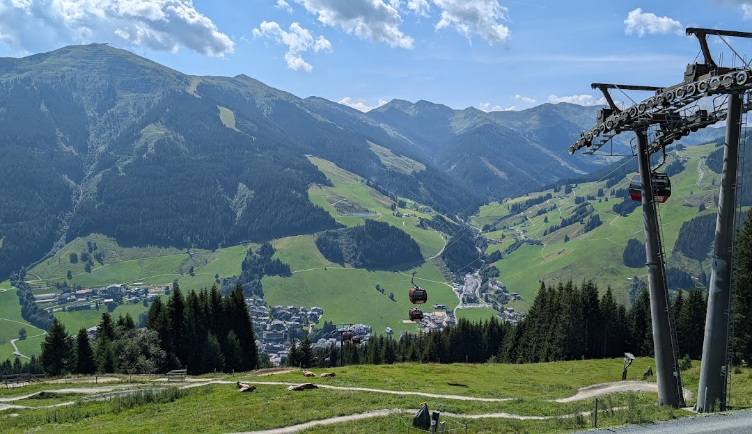 Ski resort in Reitherkogelbahn, Austria featuring a charming chalet and a ski lift, nestled against the backdrop of a mountain under a sunny sky.